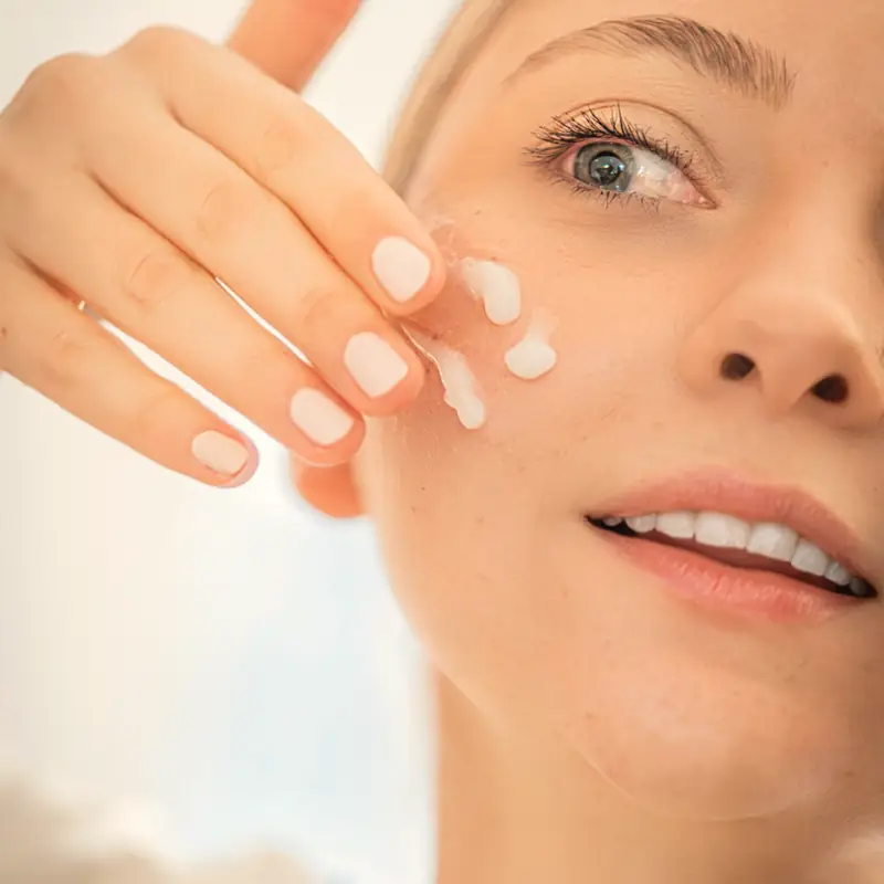 Después: rostro de una mujer aplicándose crema hidratante en la mejilla